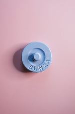 Blue fabric weight with 'Bunka' logo on a pink background